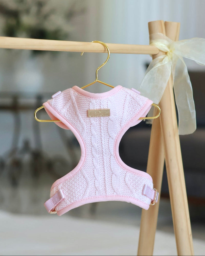 Pink dog harness on a hanger with a bow in the background