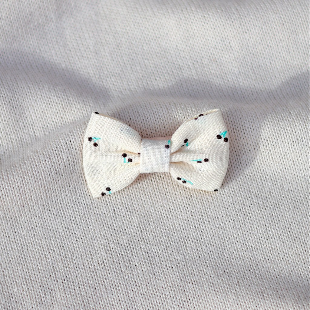 White bow with black polka dots on a gray fabric background