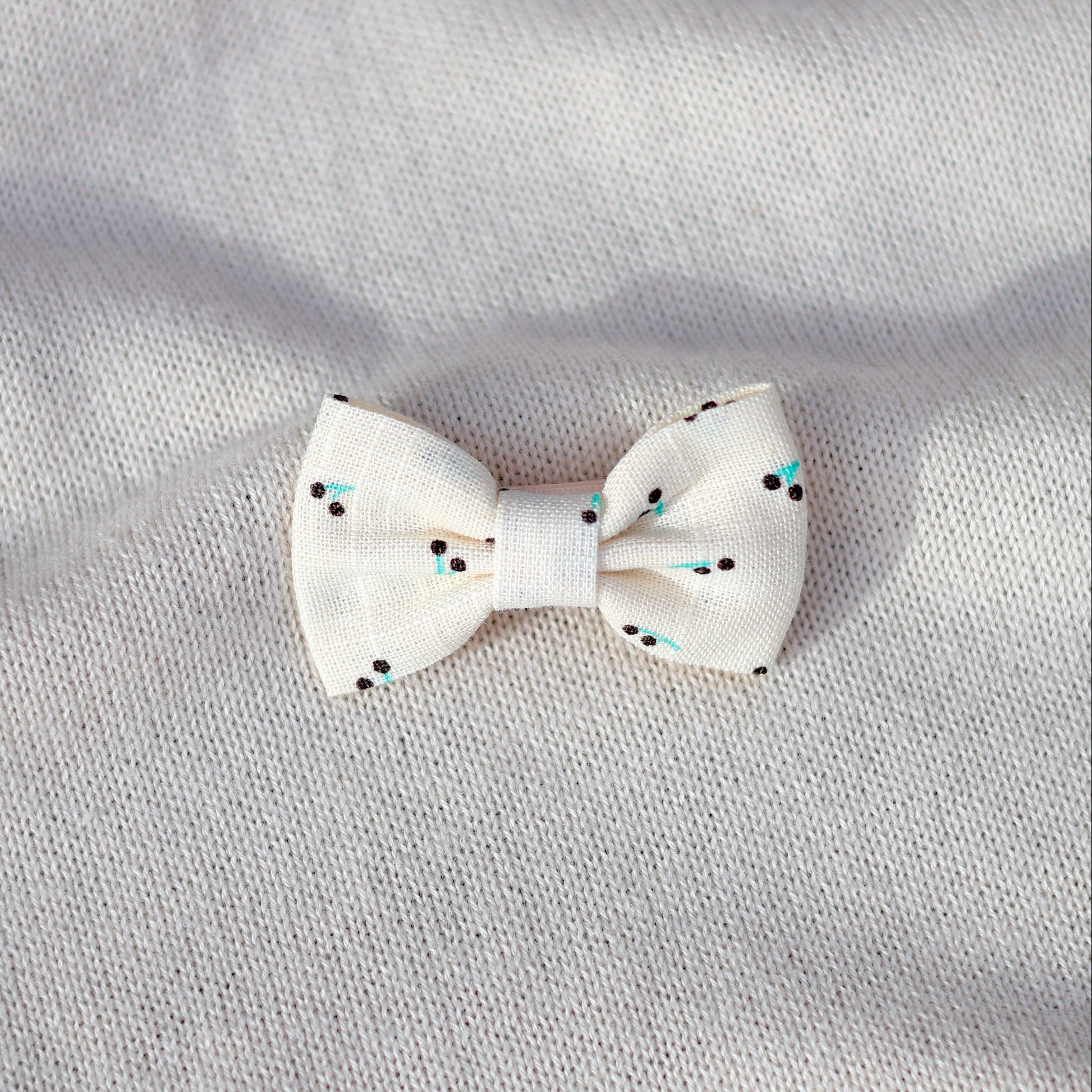 White bow with black polka dots on a gray fabric background