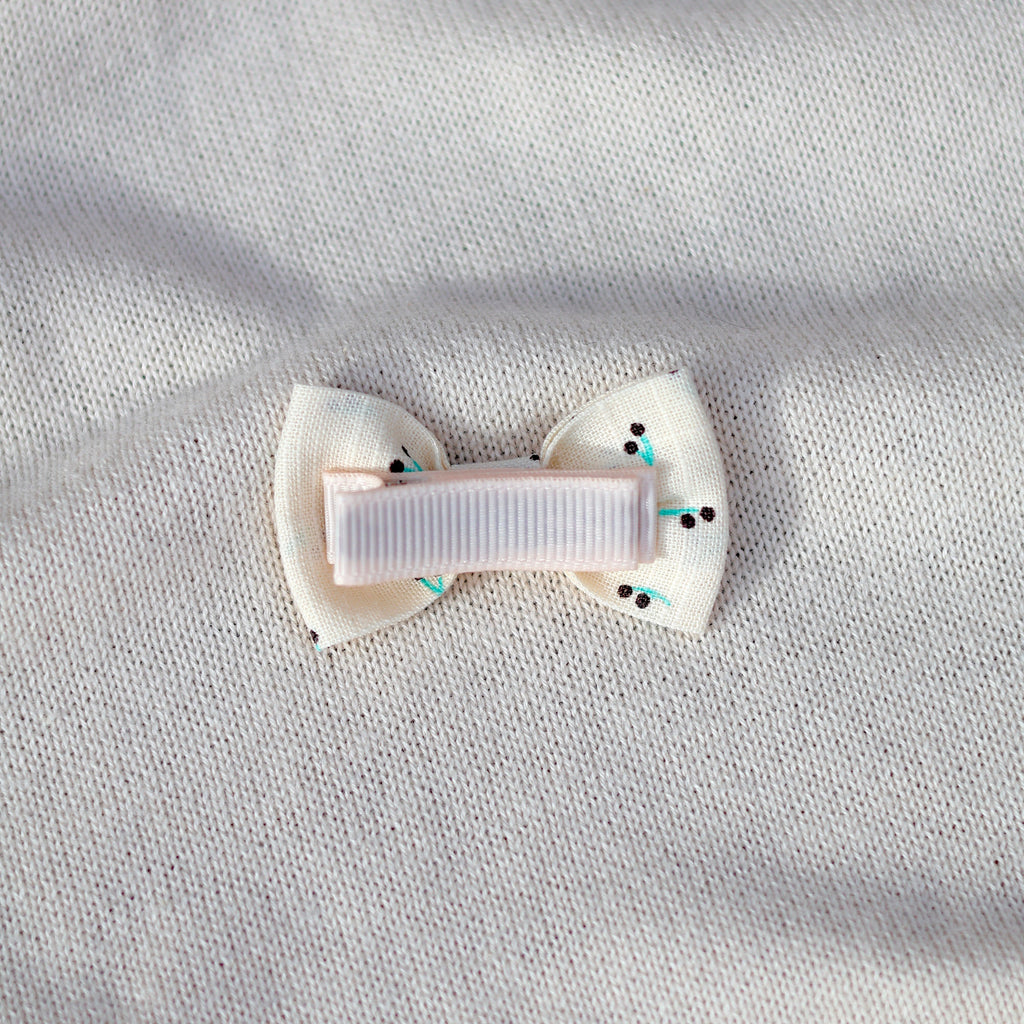 White bow hair clip on a light gray fabric background