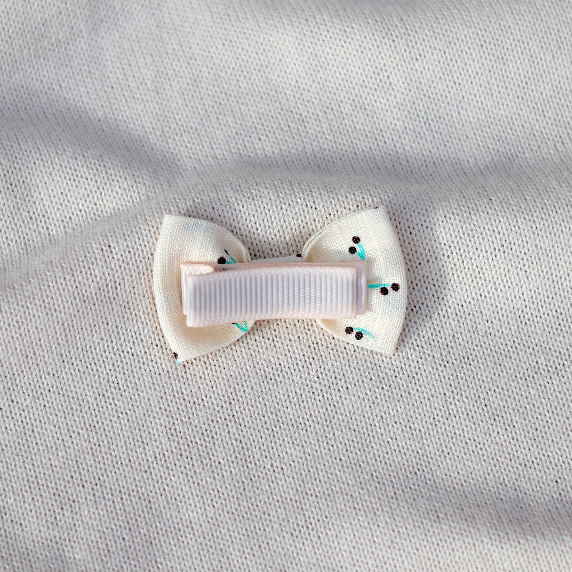 White bow hair clip on a light gray fabric background