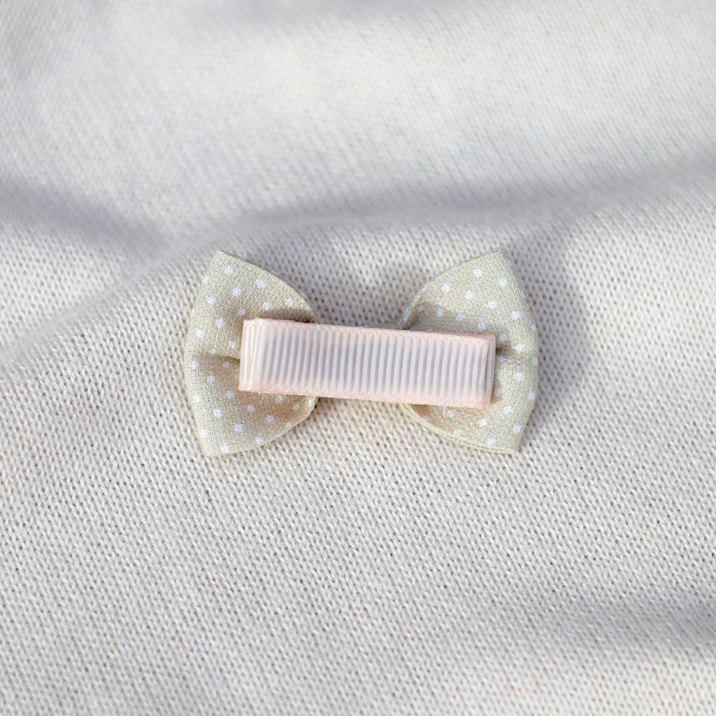 White hair bow with polka dots on a white fabric background