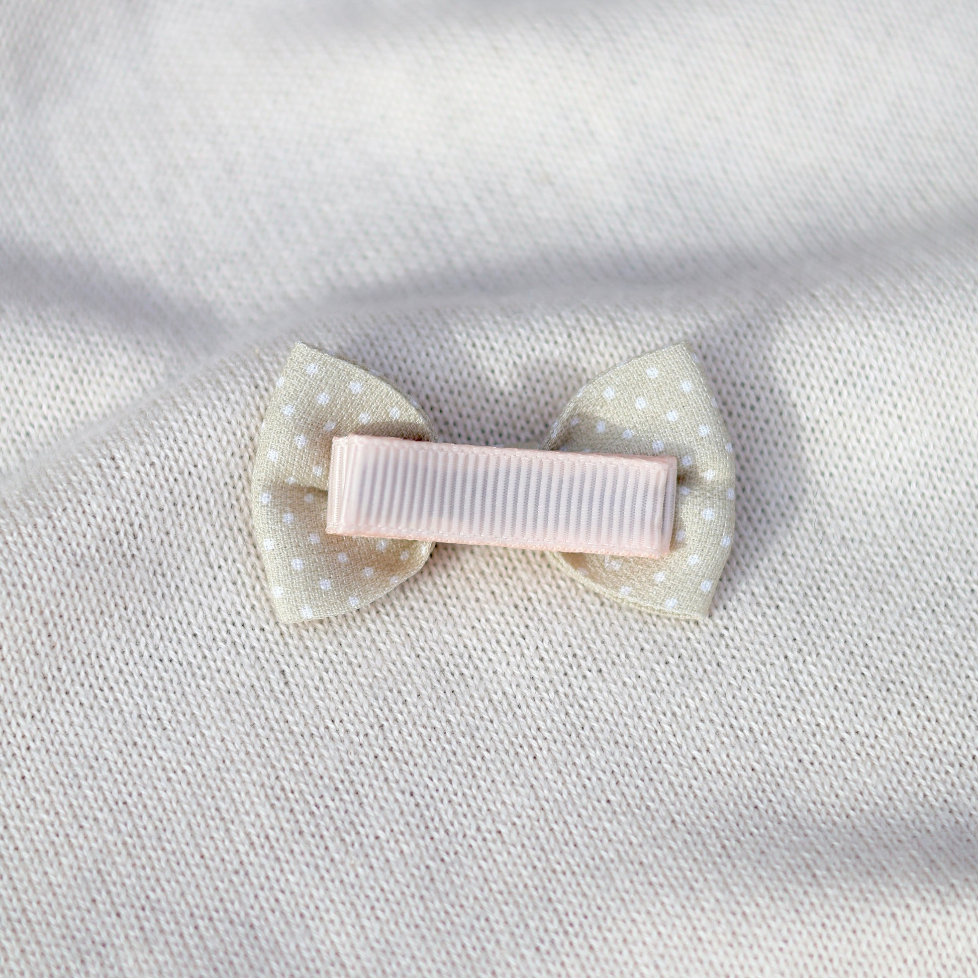 White hair bow with polka dots on a white fabric background