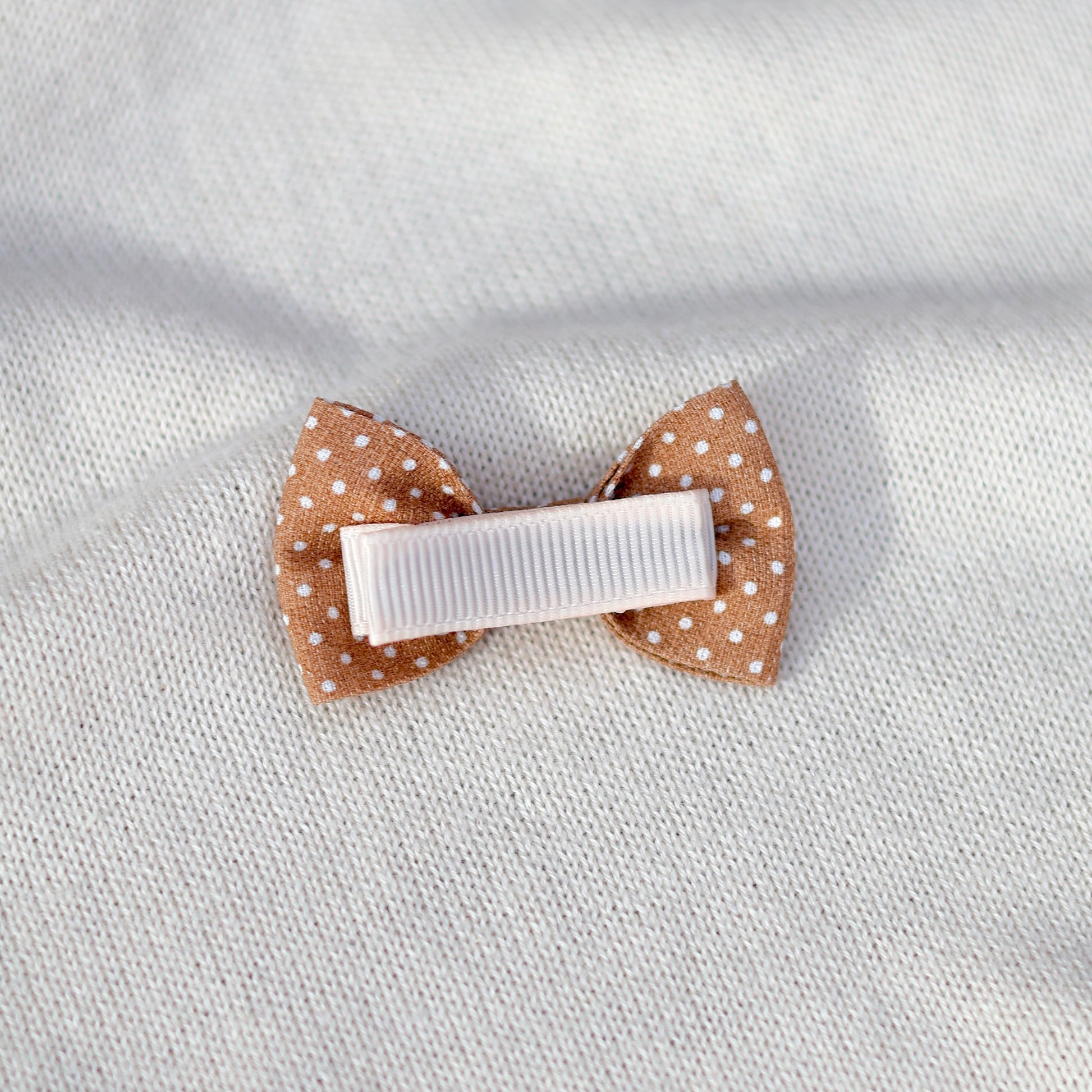 Polka dot hair clip on a textured light gray background