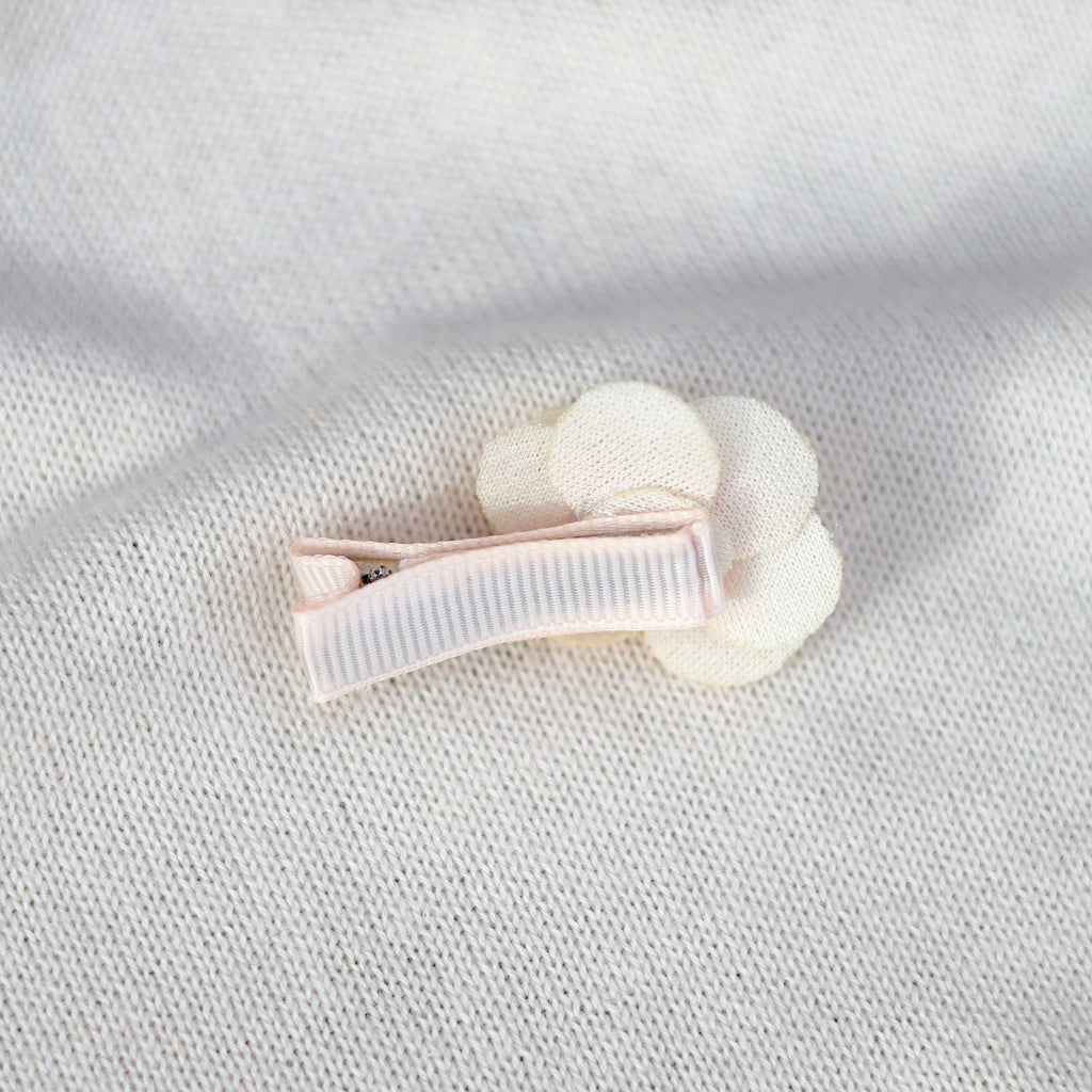 White hair clip on a textured light gray background