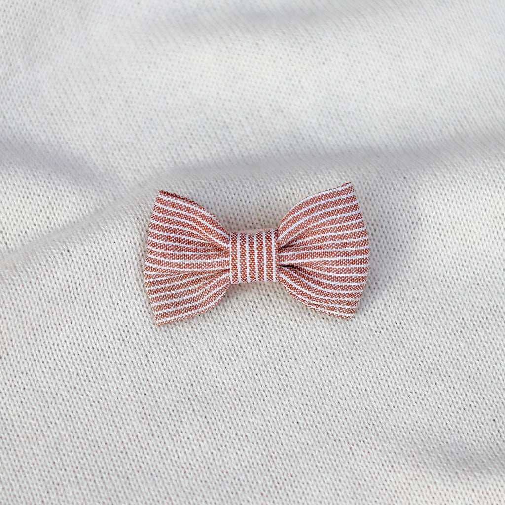 Red and white striped bow tie on a white fabric background