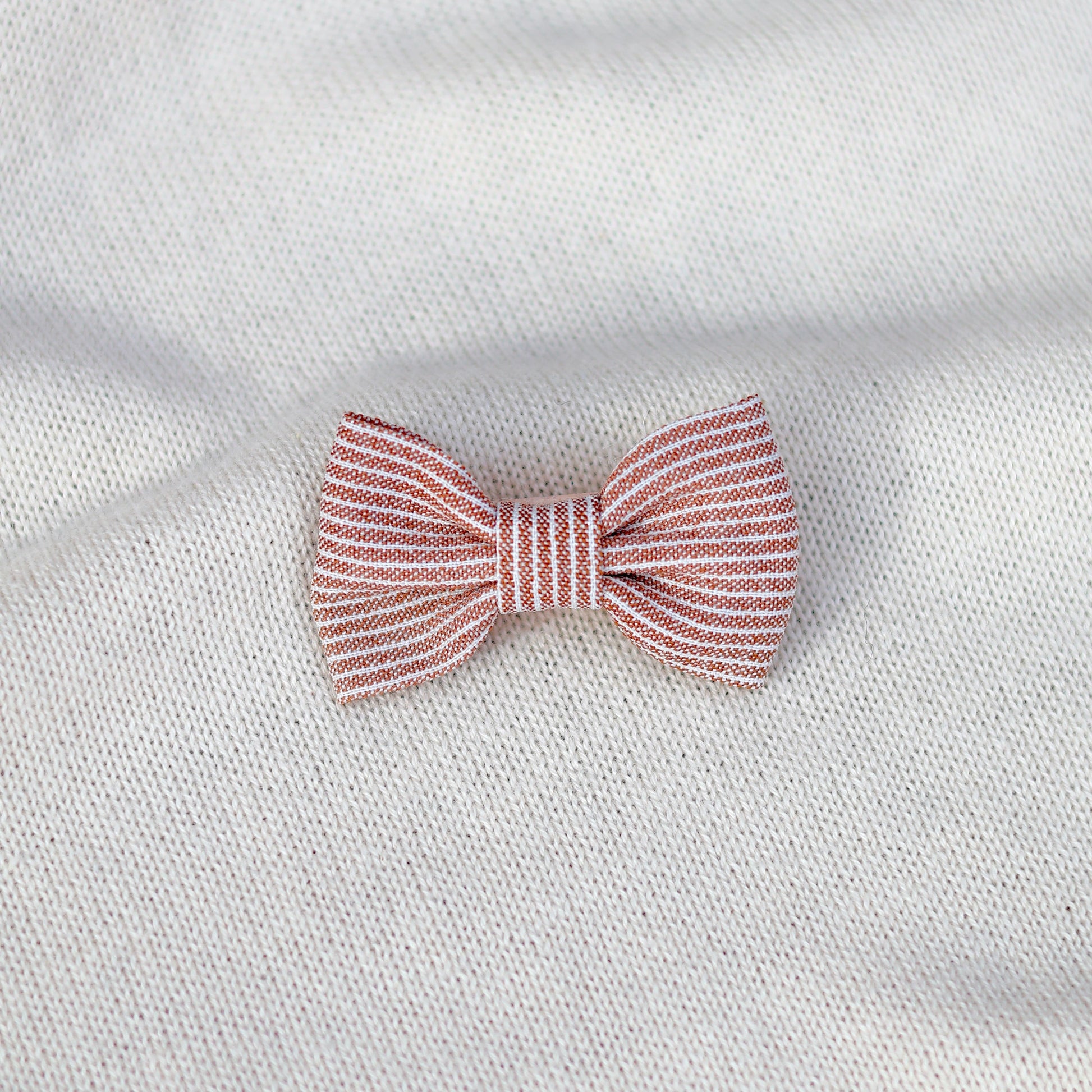 Red and white striped bow tie on a white fabric background
