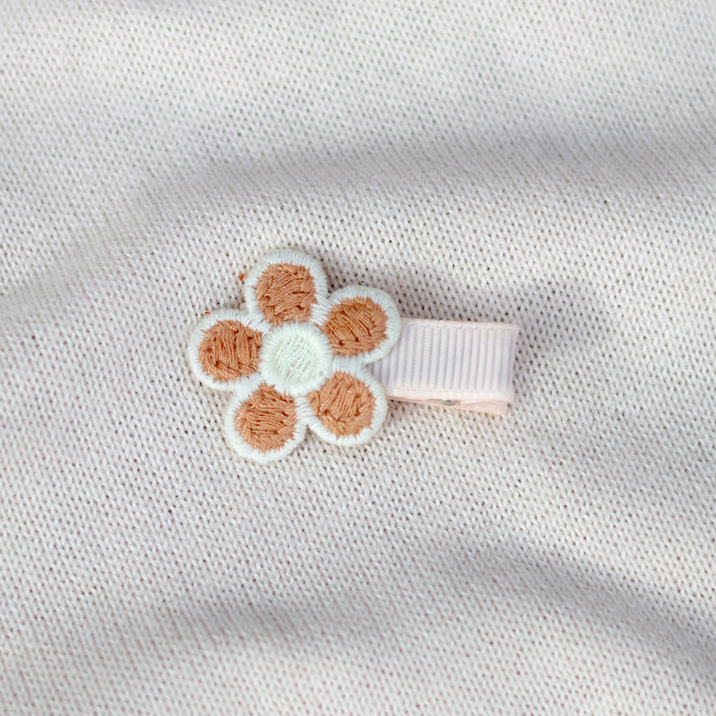 Floral hair clip on a textured white fabric background
