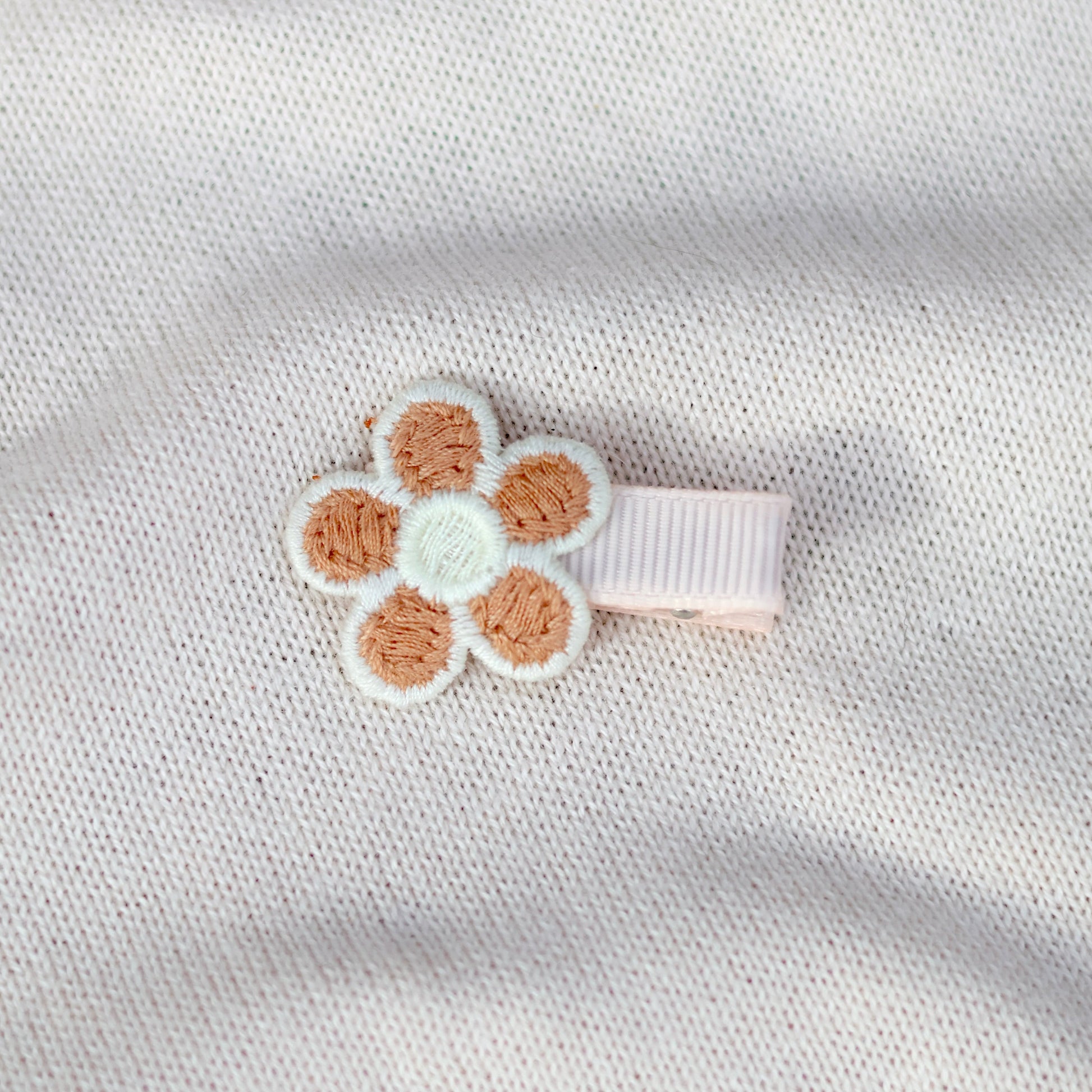 Floral hair clip on a textured white fabric background