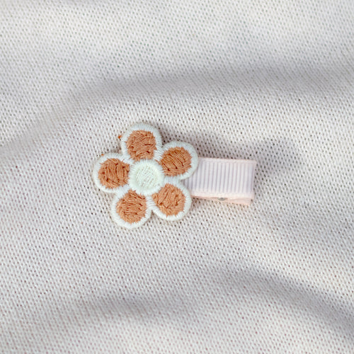 Floral hair clip on a textured white fabric background