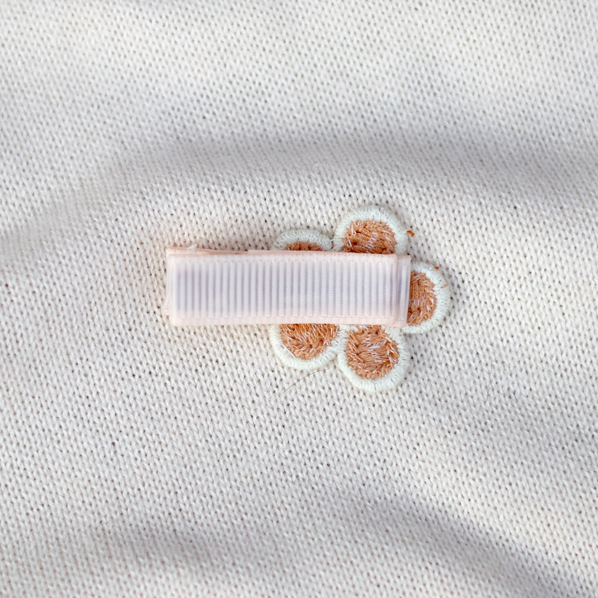 White fabric with a small white label and brown paw prints on a light gray background