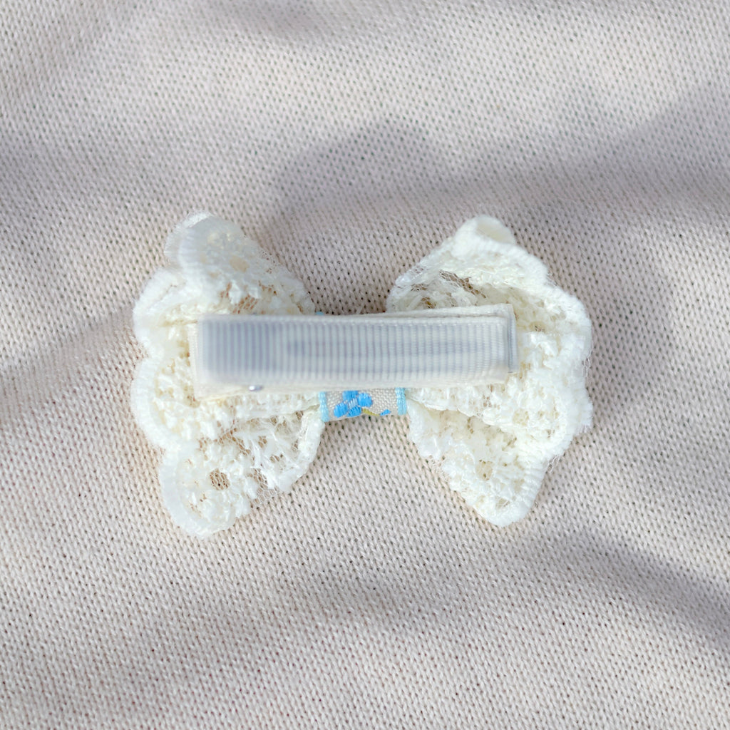White bow-shaped hair clip on a textured beige surface