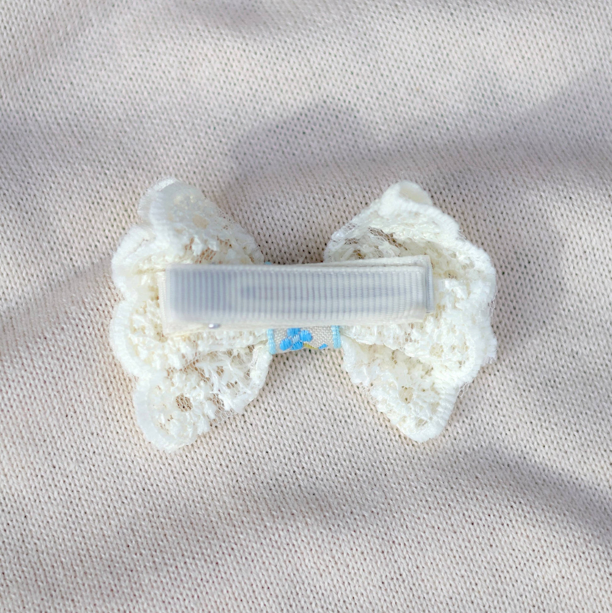 White bow-shaped hair clip on a textured beige surface