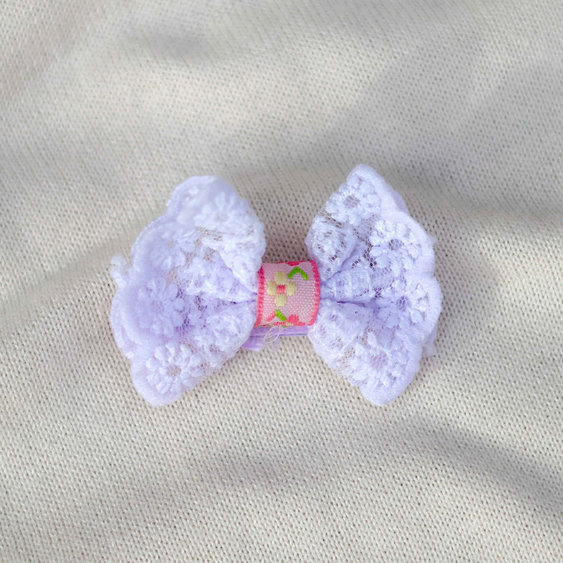 Lavender bow hair clip on a gray fabric background