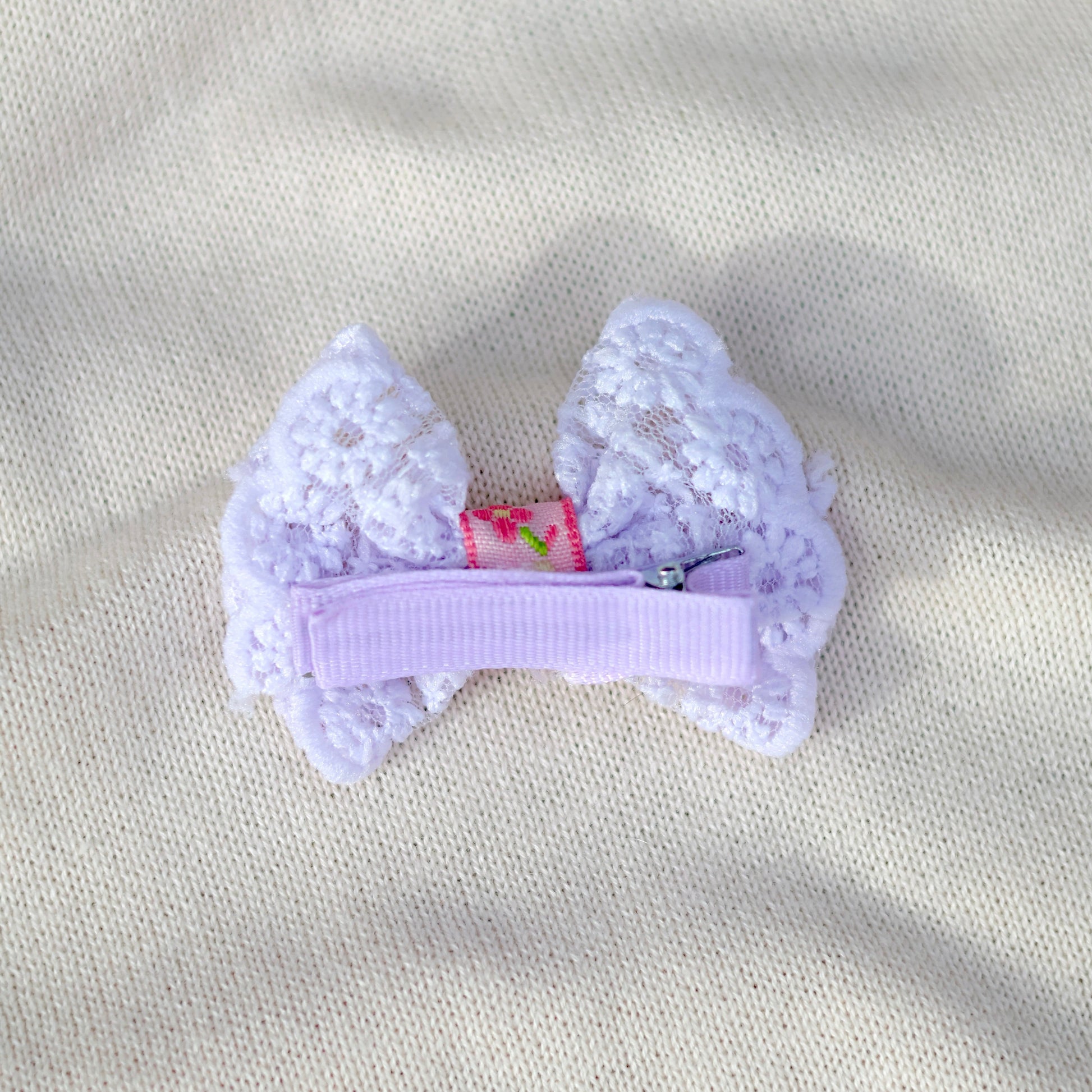 Lace bow hair clip on a beige fabric background