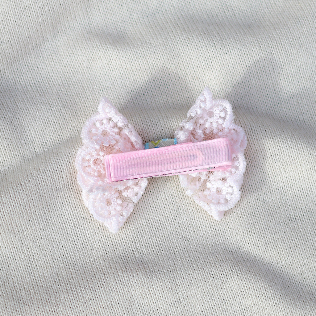 Pink hair clip with lace details on a gray fabric background