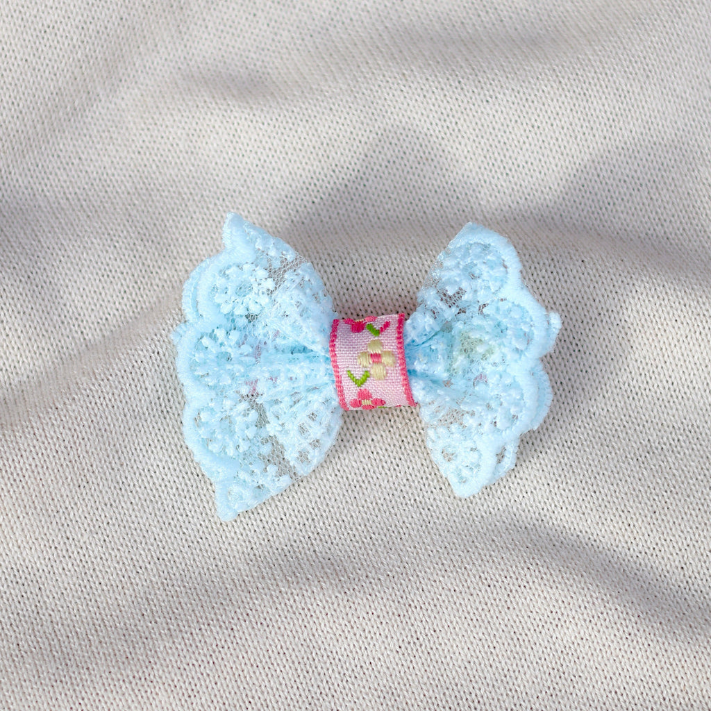 Light blue bow with a pink center on a gray fabric background