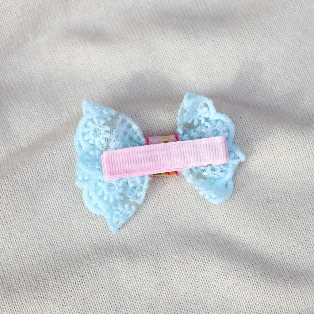 Light blue bow hair clip on a gray fabric background