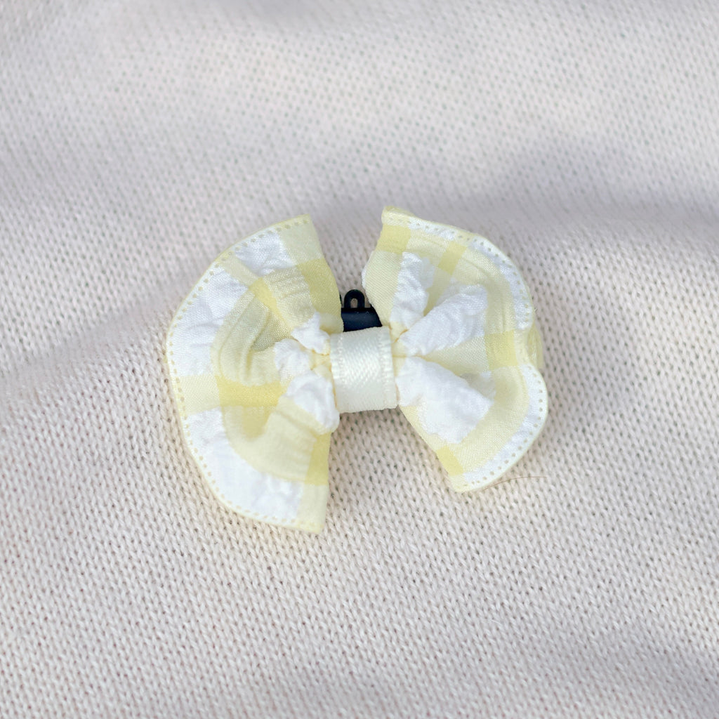 White and yellow bow hair clip on a light gray background