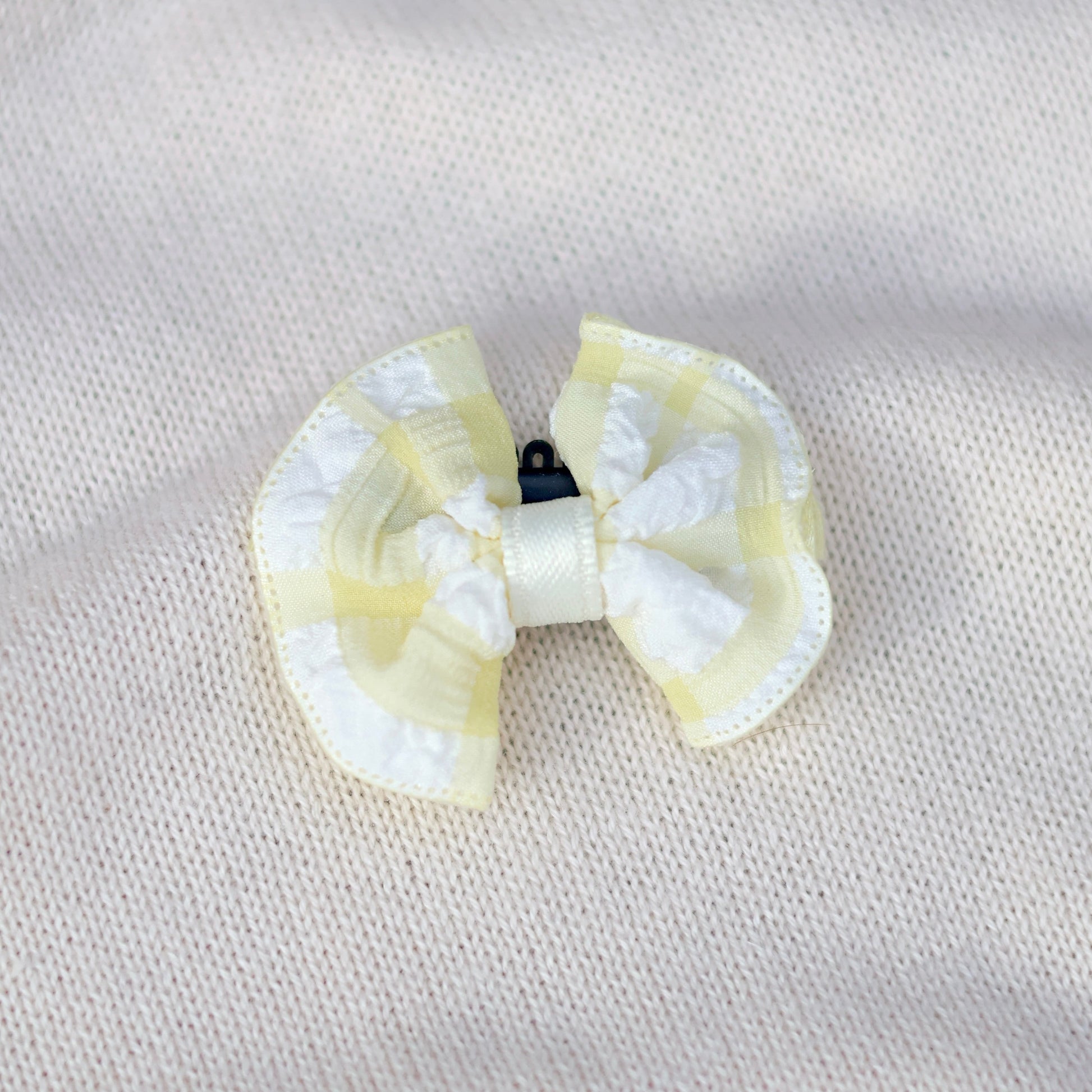 White and yellow bow hair clip on a light gray background