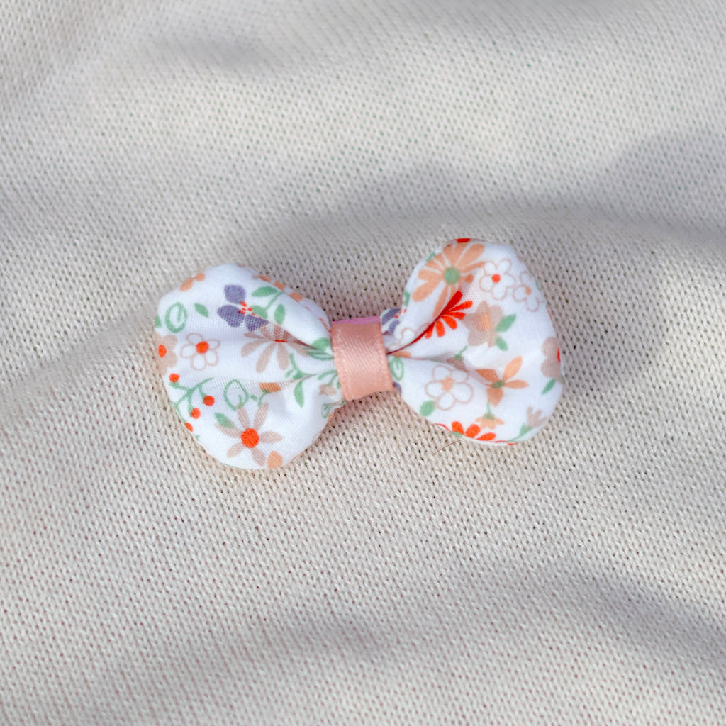 Floral bow hair clip on a textured beige background