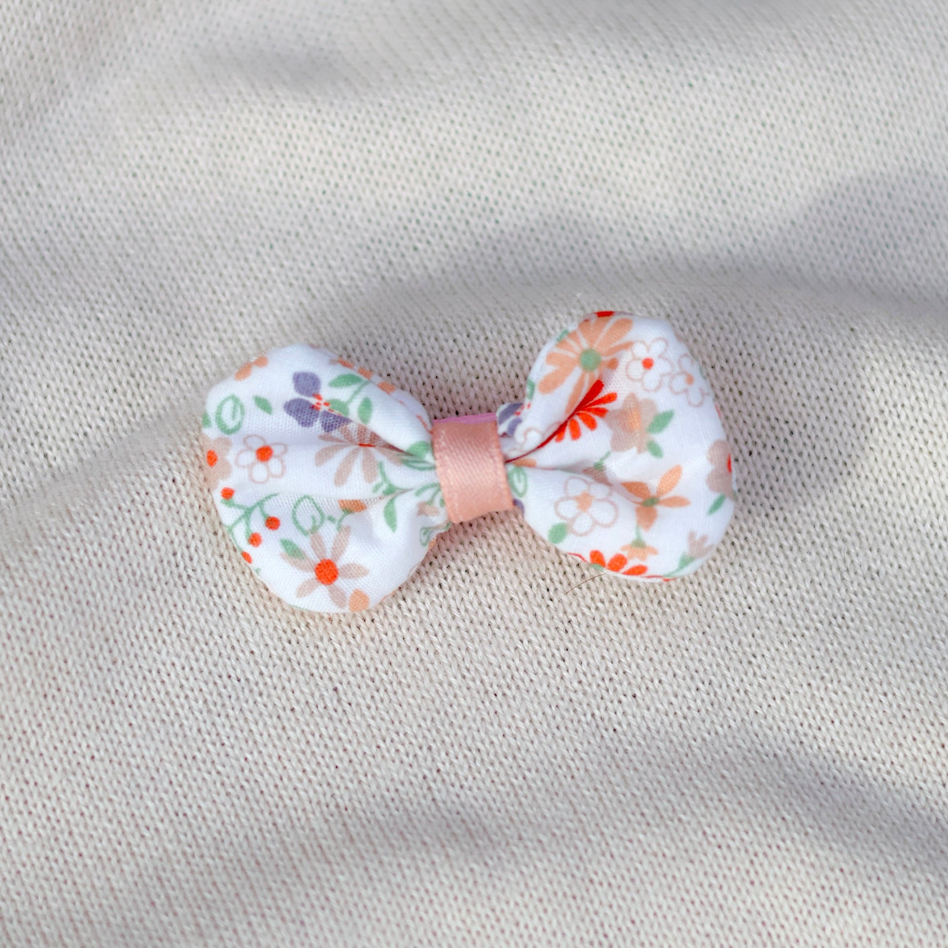 Floral bow hair clip on a textured beige background