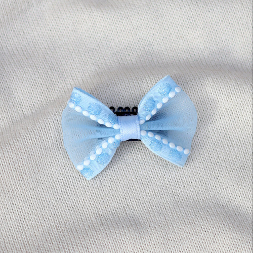Light blue bow with white polka dots on a gray fabric background