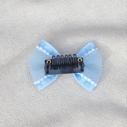 Blue bow hair clip on a light gray fabric background