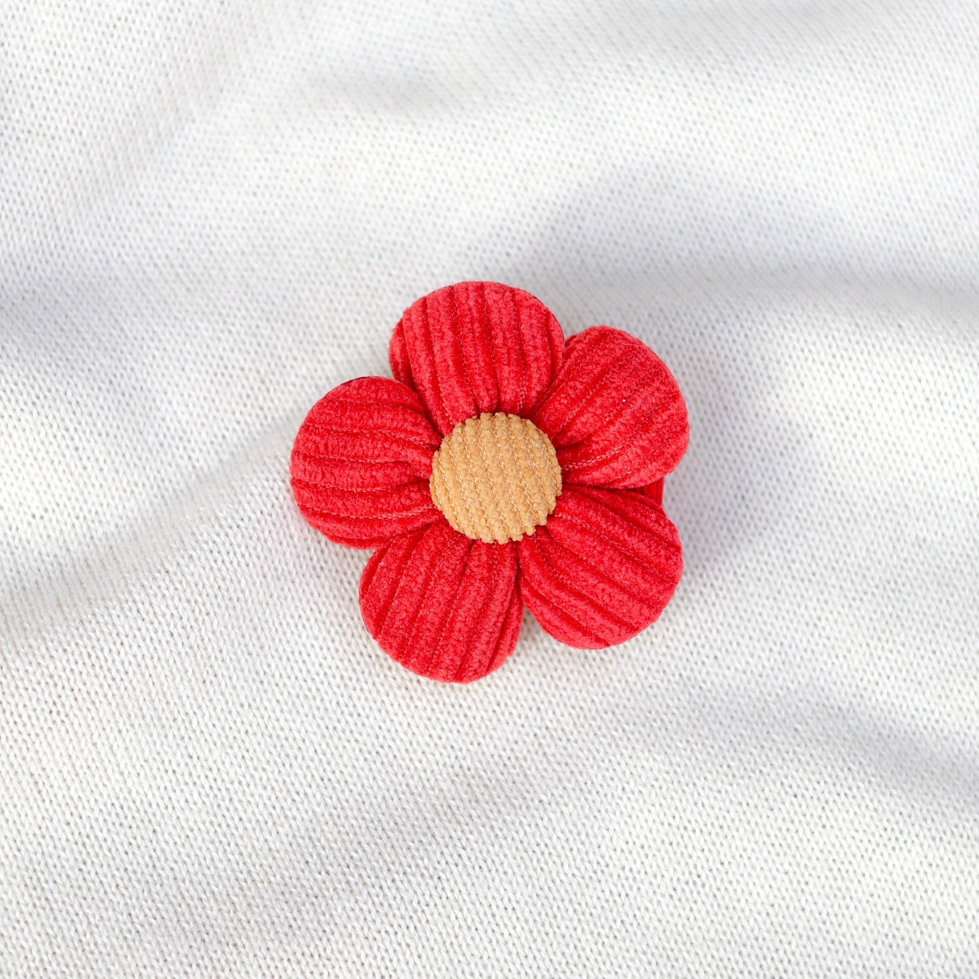 Red flower-shaped object on a white fabric background