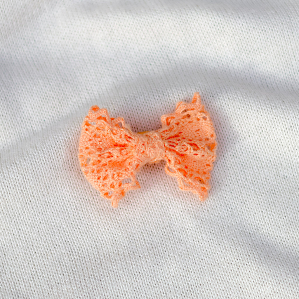 Small orange bow on a white fabric background