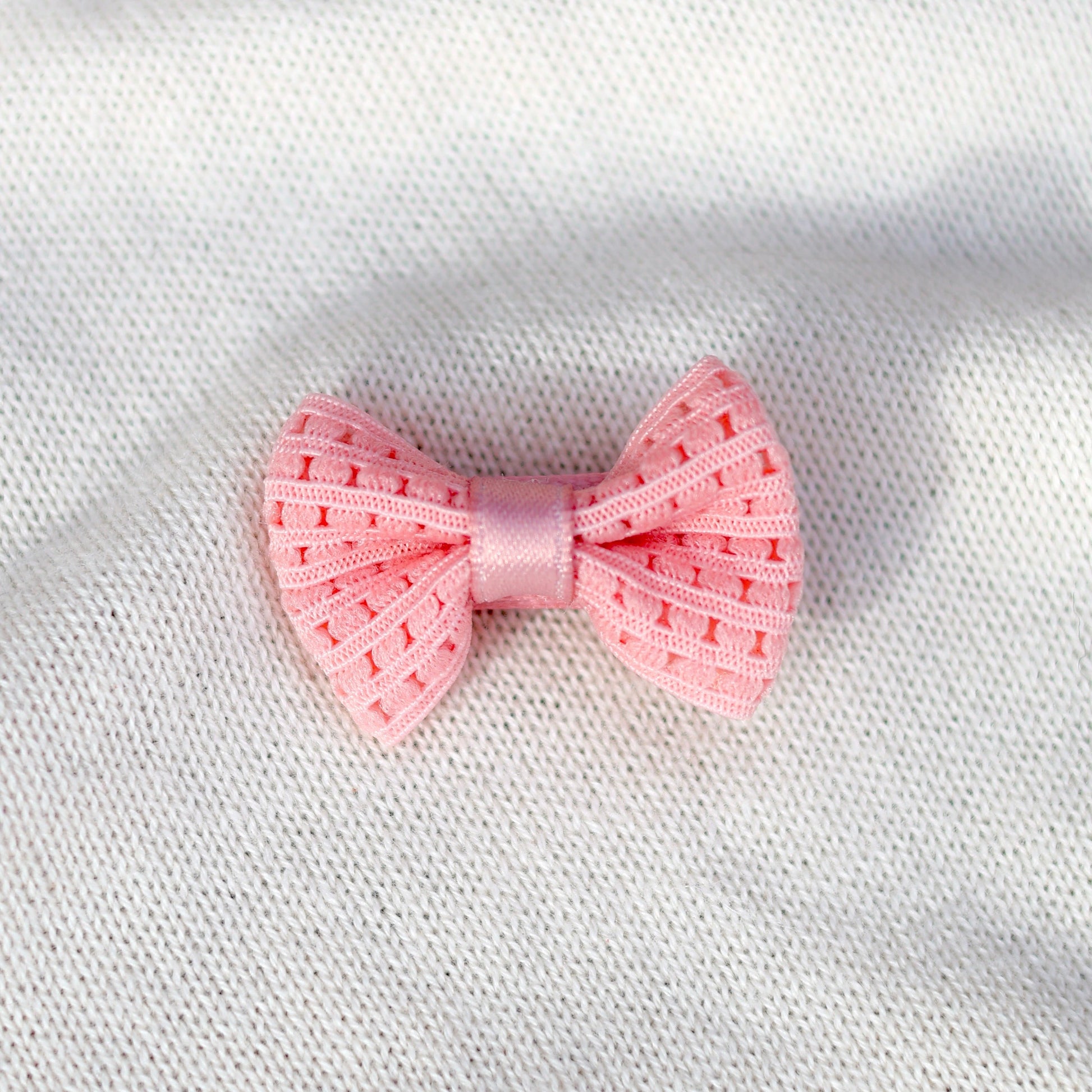 Pink bow on a white fabric background