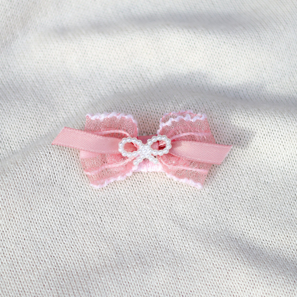 Pink bow with lace details on a white fabric background