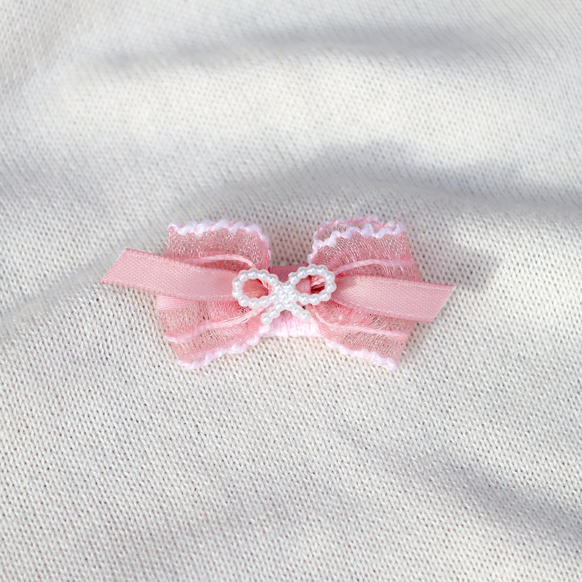 Pink bow with lace details on a white fabric background