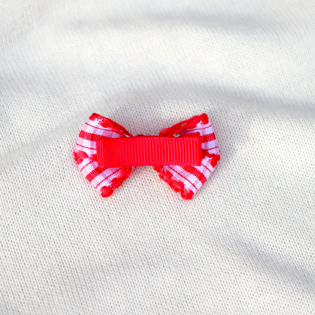 Red and white striped bow on a white fabric background