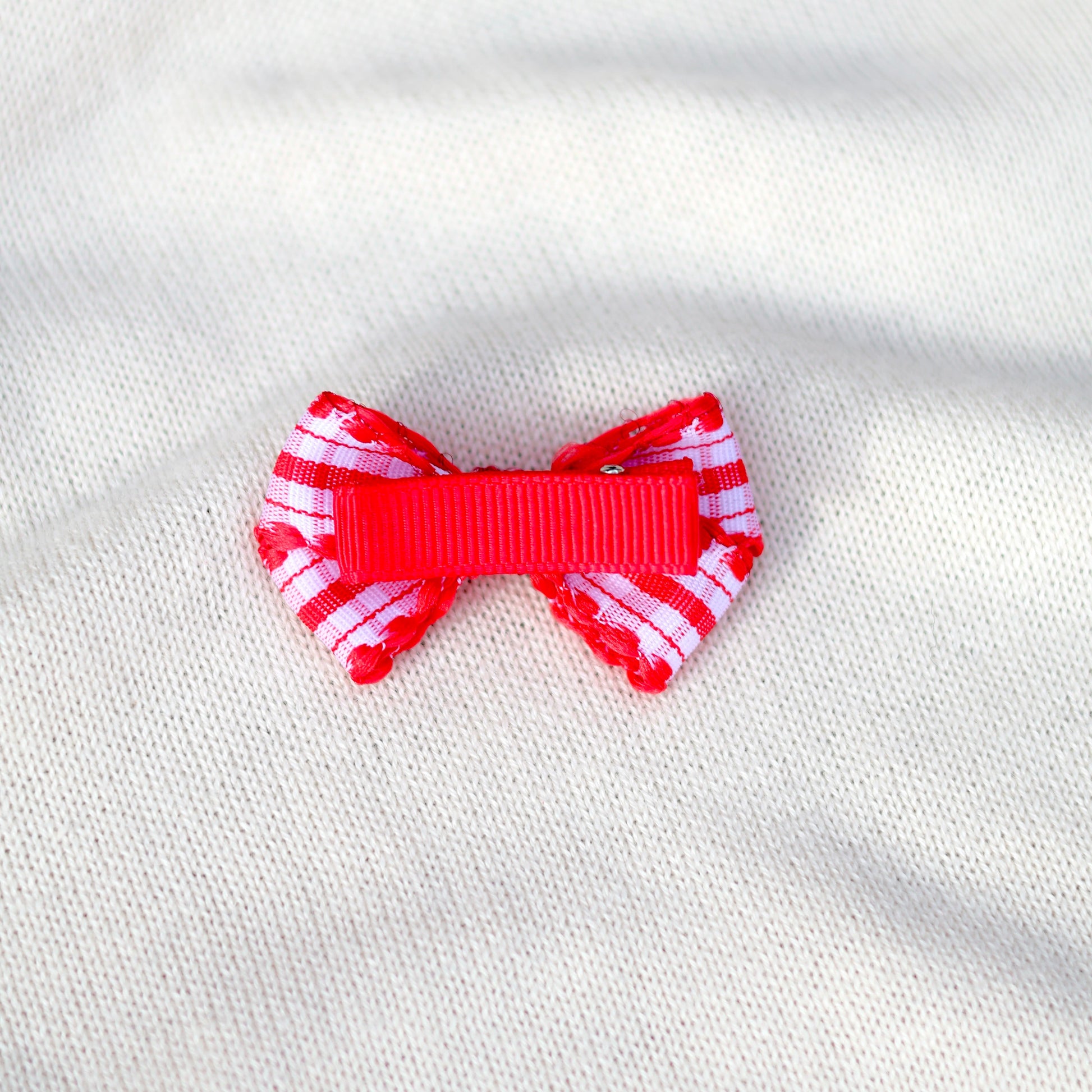 Red and white striped bow on a white fabric background