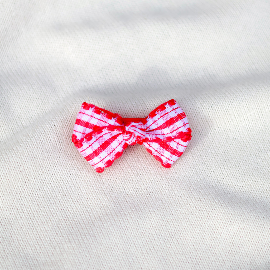 Red and white striped bow on a textured white background