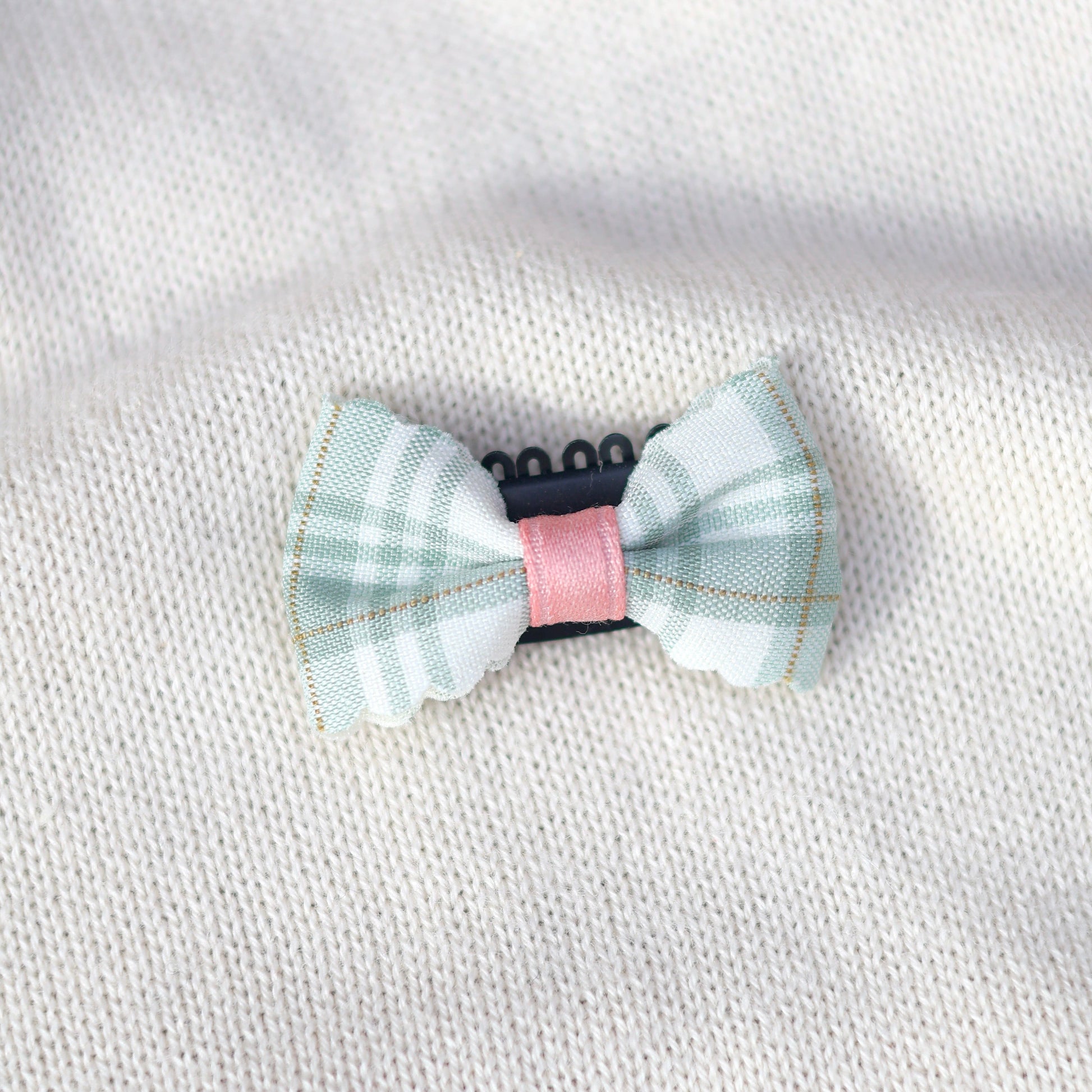 Checkered bow tie with pink center on a white fabric background