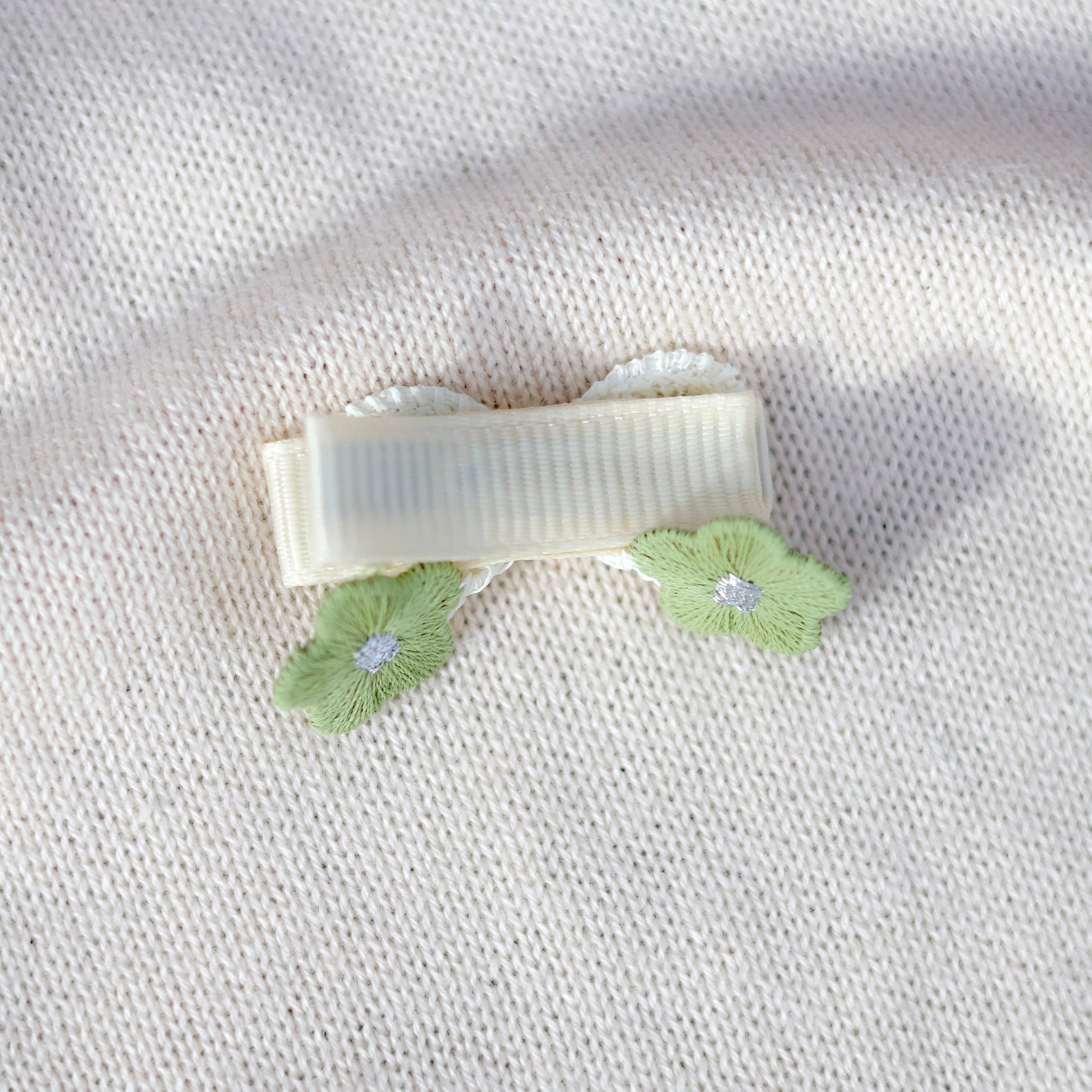 Hair clip with green leaves on a textured white background