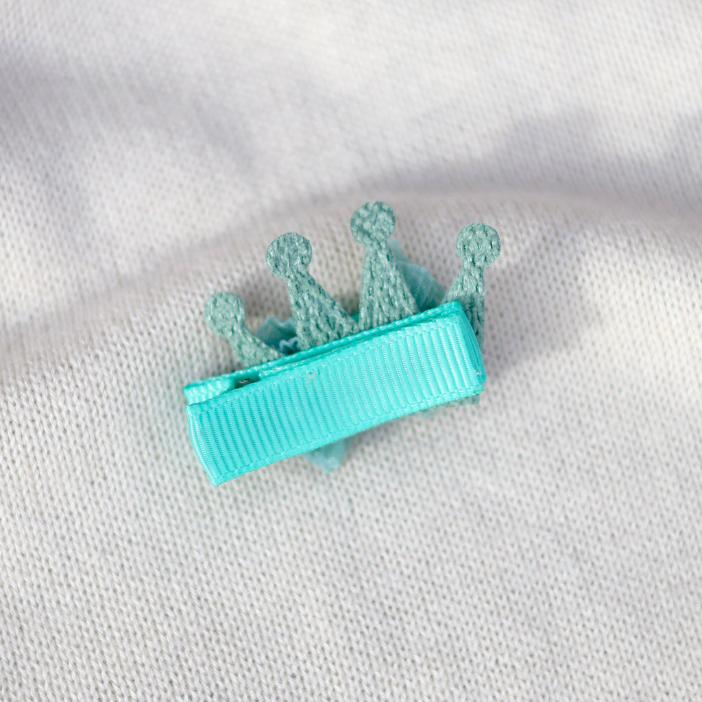 Turquoise hair clip with floral design on a white fabric background