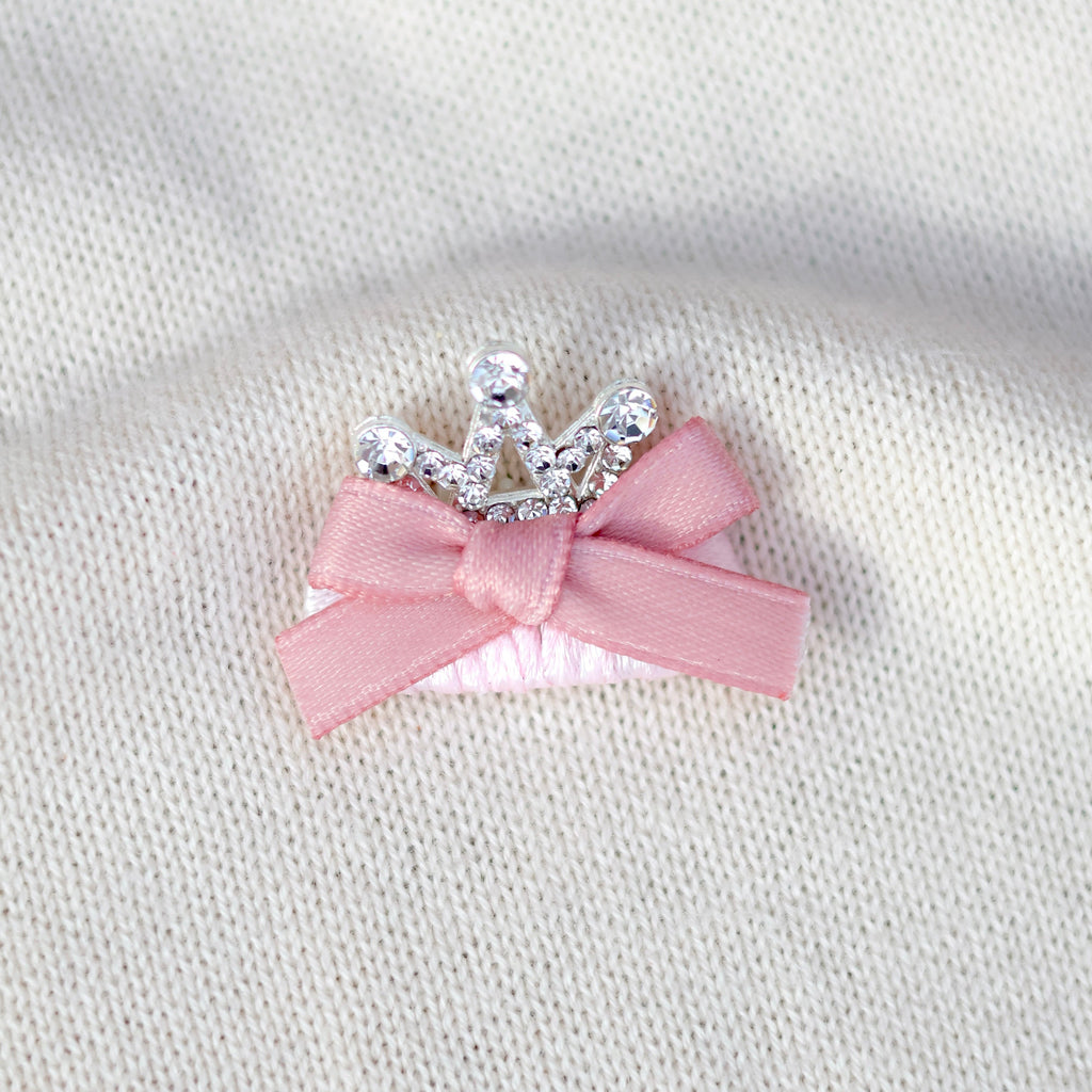 Pink bow with silver tiara on a white fabric background