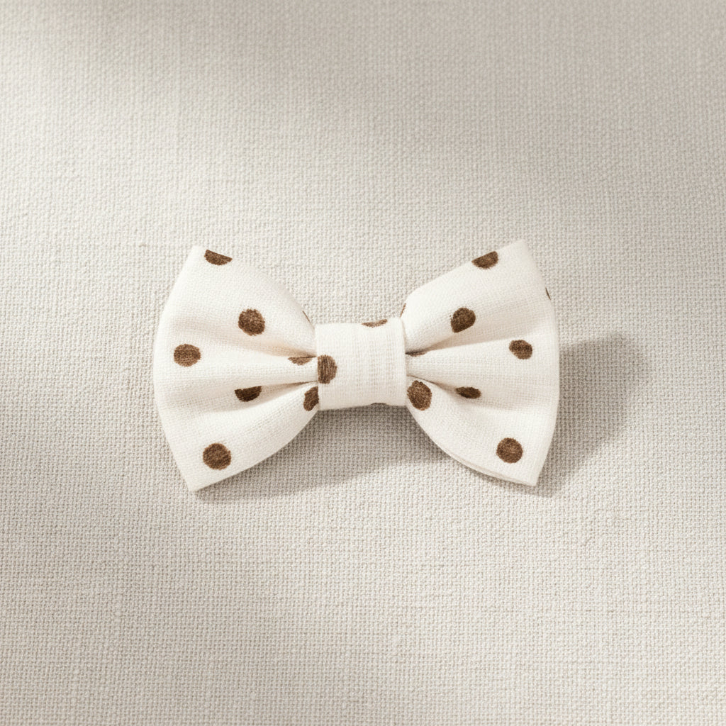 White bow with brown polka dots on a beige fabric background