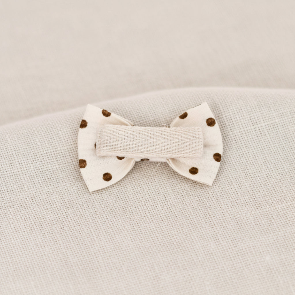 White knitted bow with brown buttons on a beige fabric background