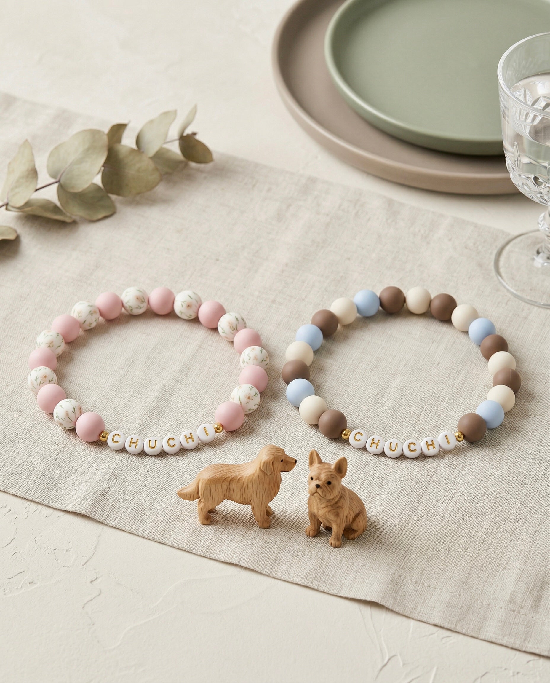 Two beaded bracelets with 'CHUCHI' on a tablecloth with dog figurines.